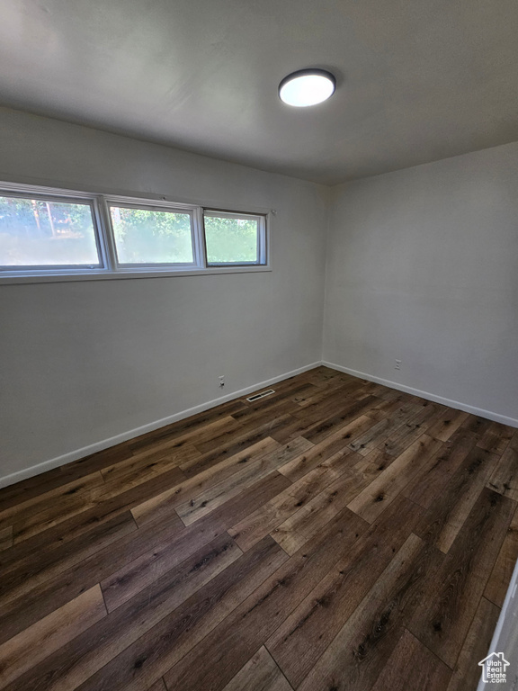 Unfurnished room with dark wood-type flooring and baseboards