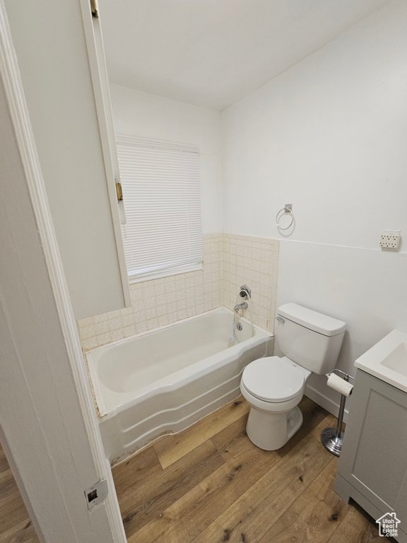 Bathroom with wood finished floors, a bath, toilet, and vanity