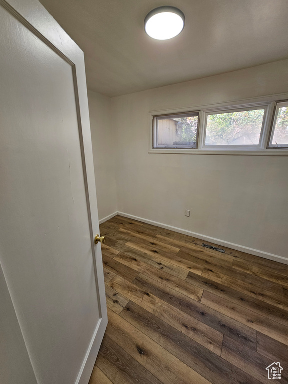 Empty room featuring dark wood finished floors and baseboards