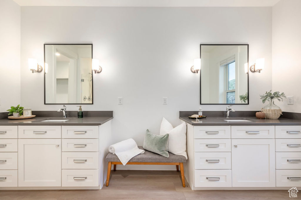 Full bath featuring two vanities, wood finished floors, and baseboards