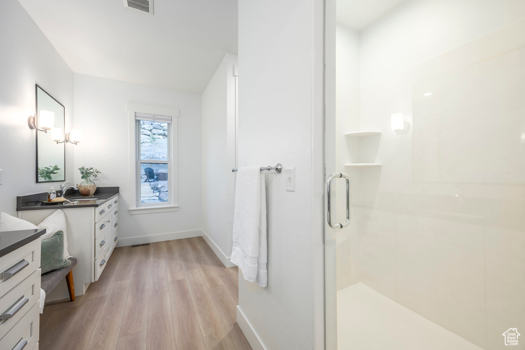 Full bath with wood finished floors, a shower stall, vanity, and baseboards