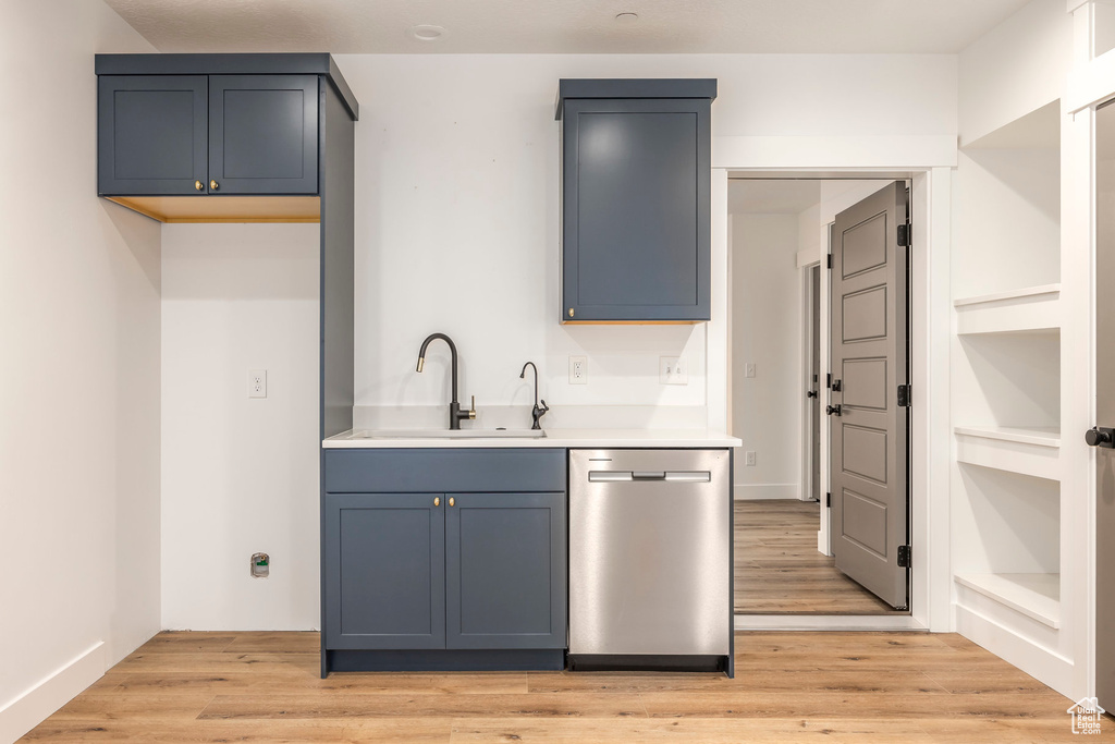 Kitchen with dishwasher, a sink, light countertops, and light wood finished floors