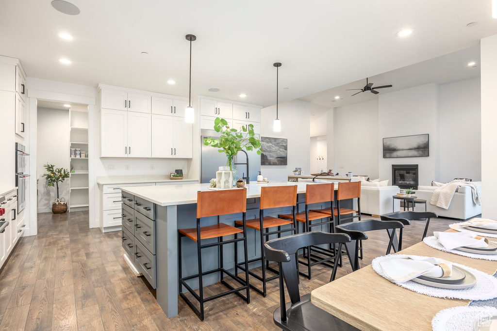Kitchen featuring a center island, ceiling fan, white cabinets, a kitchen breakfast bar, and light countertops