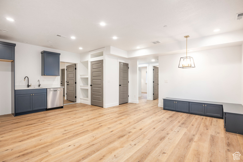 Kitchen featuring stainless steel dishwasher, a sink, light wood-style floors, recessed lighting, and light countertops