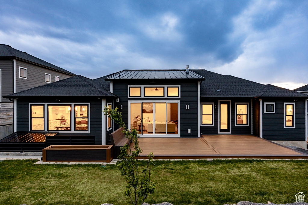 Back of house with a standing seam roof, a deck, and a yard