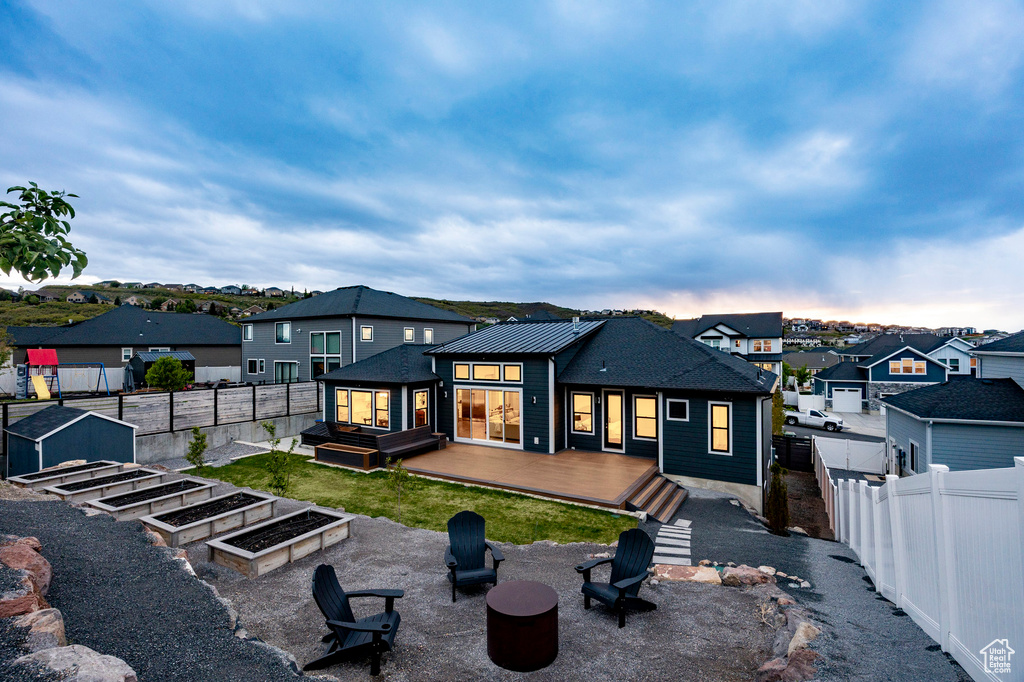 Back of property with a fire pit, a fenced backyard, a deck, a residential view, and a vegetable garden