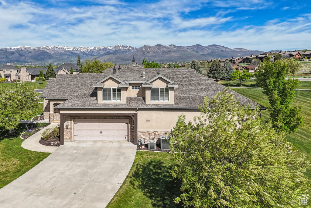 View of front facade featuring stucco siding, stone siding, driveway, and a garage