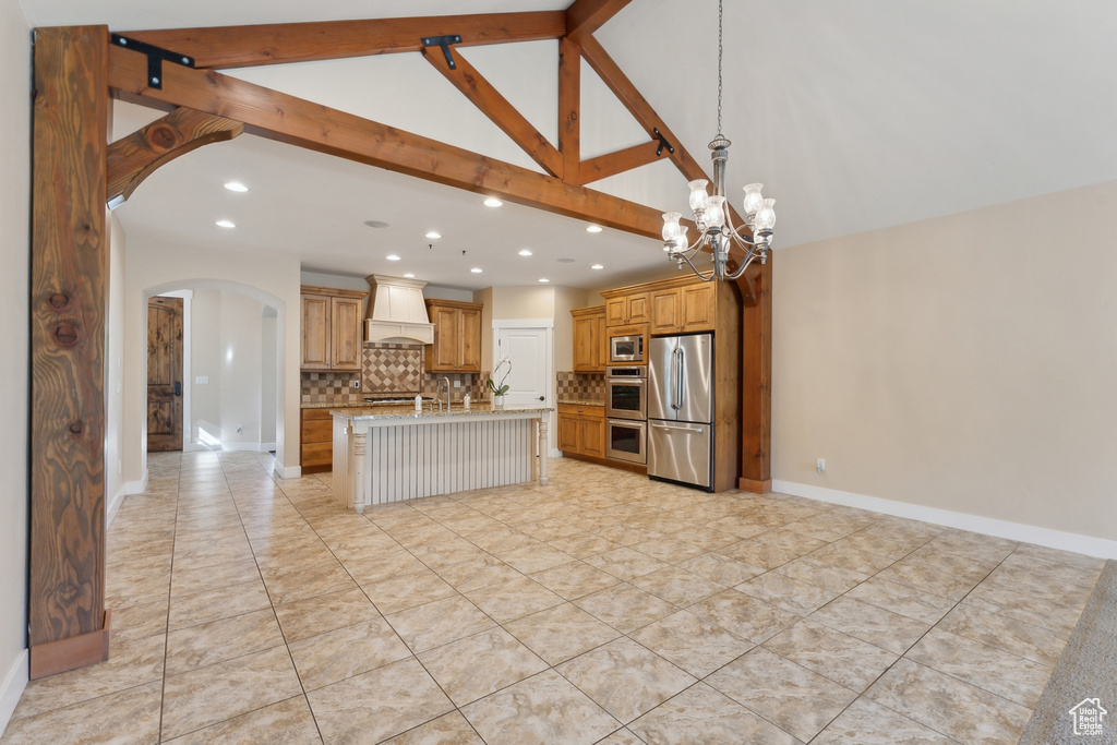 Kitchen with custom exhaust hood, stainless steel appliances, arched walkways, backsplash, and recessed lighting