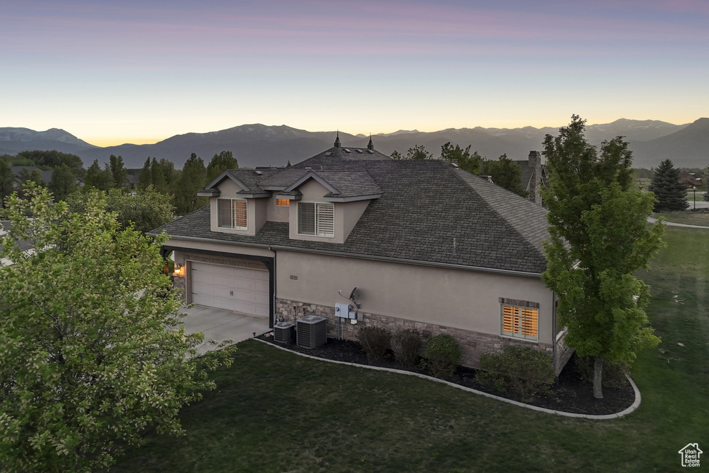 View of front of home with stucco siding, stone siding, concrete driveway, cooling unit, and a mountain view