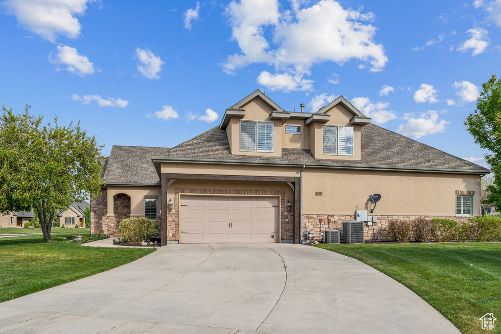 Traditional-style home featuring stucco siding, stone siding, driveway, and a front lawn