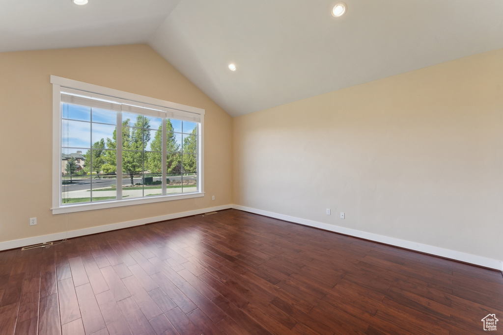 Spare room featuring lofted ceiling, dark wood finished floors, baseboards, and recessed lighting