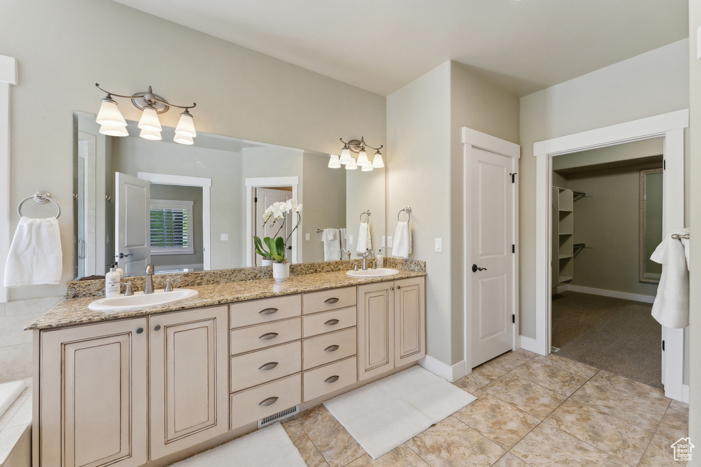 Full bath featuring double vanity, tile patterned flooring, and a walk in closet