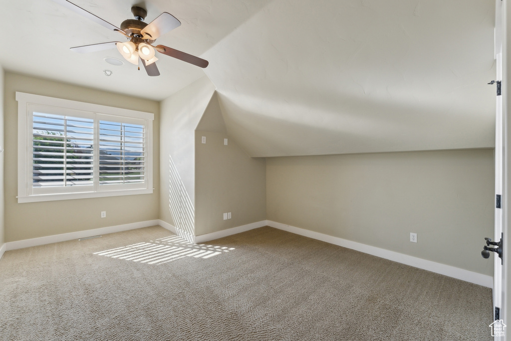 Additional living space featuring carpet, ceiling fan, baseboards, and vaulted ceiling