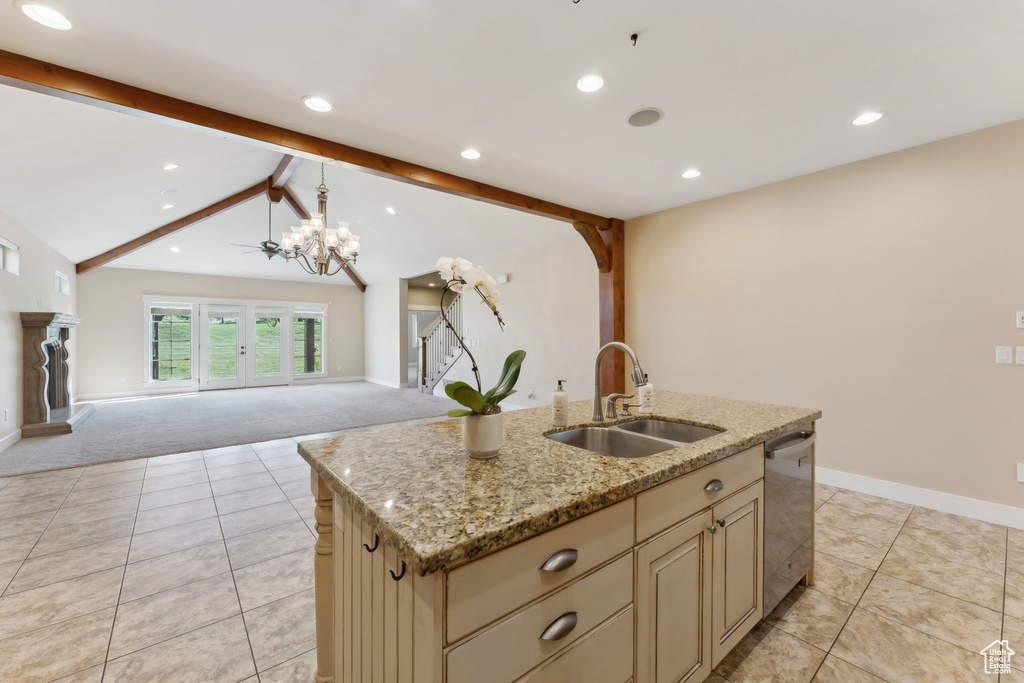 Kitchen with a sink, cream cabinets, dishwasher, open floor plan, and baseboards