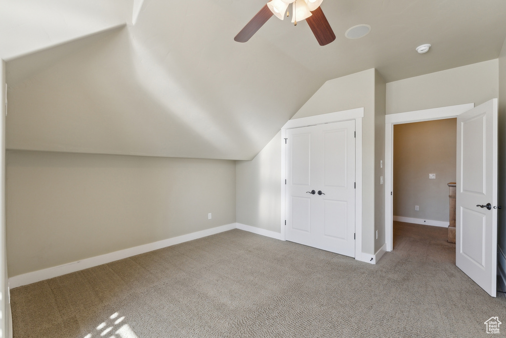Additional living space with vaulted ceiling, carpet flooring, a ceiling fan, and baseboards