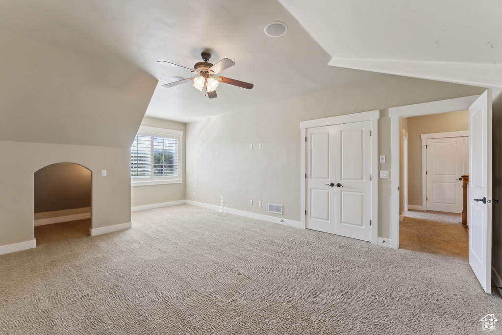 Additional living space with lofted ceiling, a ceiling fan, carpet floors, baseboards, and arched walkways