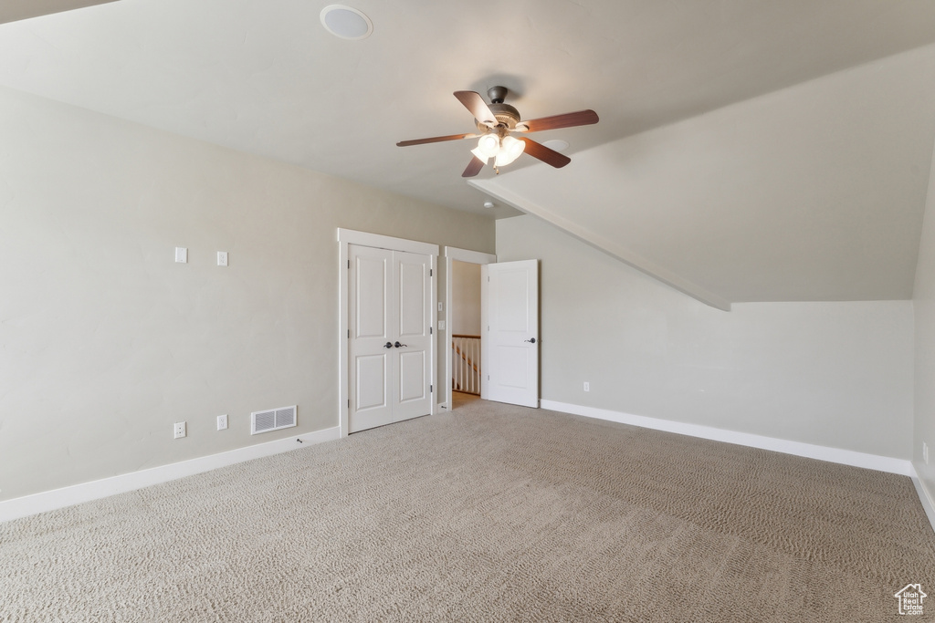 Additional living space with a ceiling fan, carpet, baseboards, and vaulted ceiling