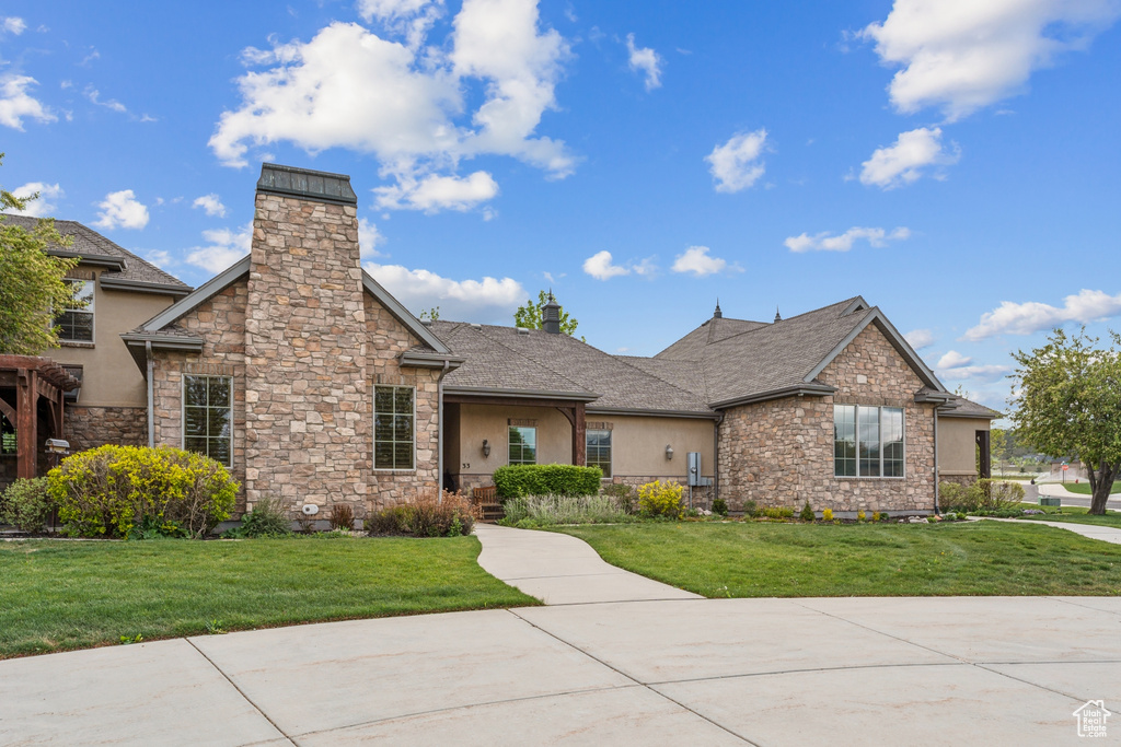 View of front of home with stone siding, a chimney, and a front yard