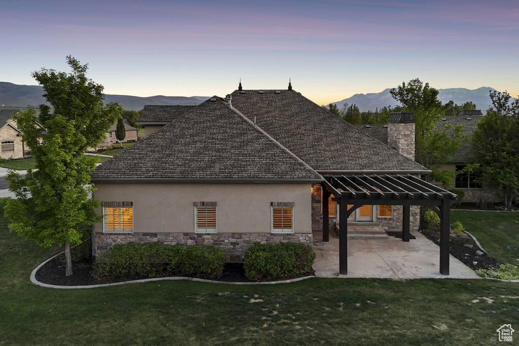 View of side of property with stone siding, a pergola, stucco siding, and a lawn