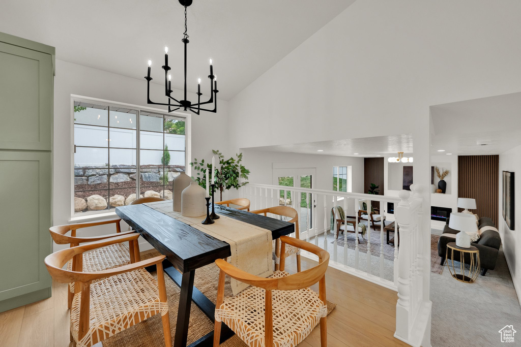 Dining area featuring a chandelier, light wood-style flooring, and high vaulted ceiling