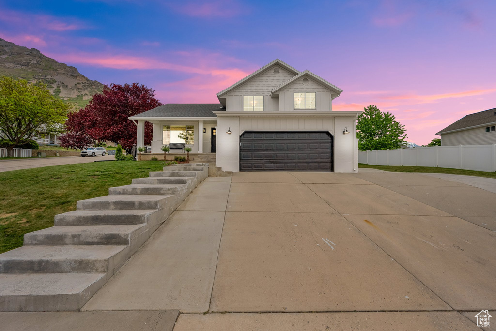 View of front of house with concrete driveway, an attached garage, and a porch