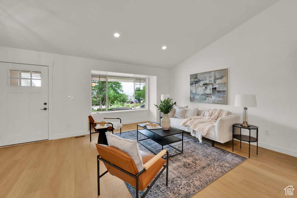 Living area featuring light wood-style flooring, lofted ceiling, baseboards, and recessed lighting