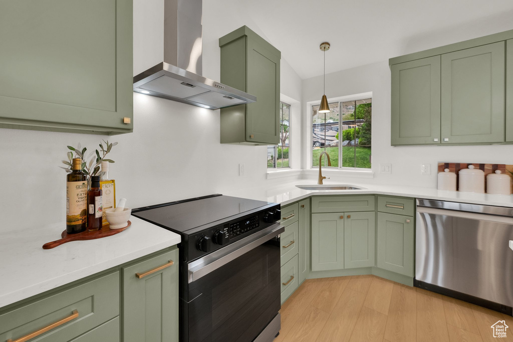Kitchen featuring green cabinetry, wall chimney exhaust hood, electric range, and stainless steel dishwasher