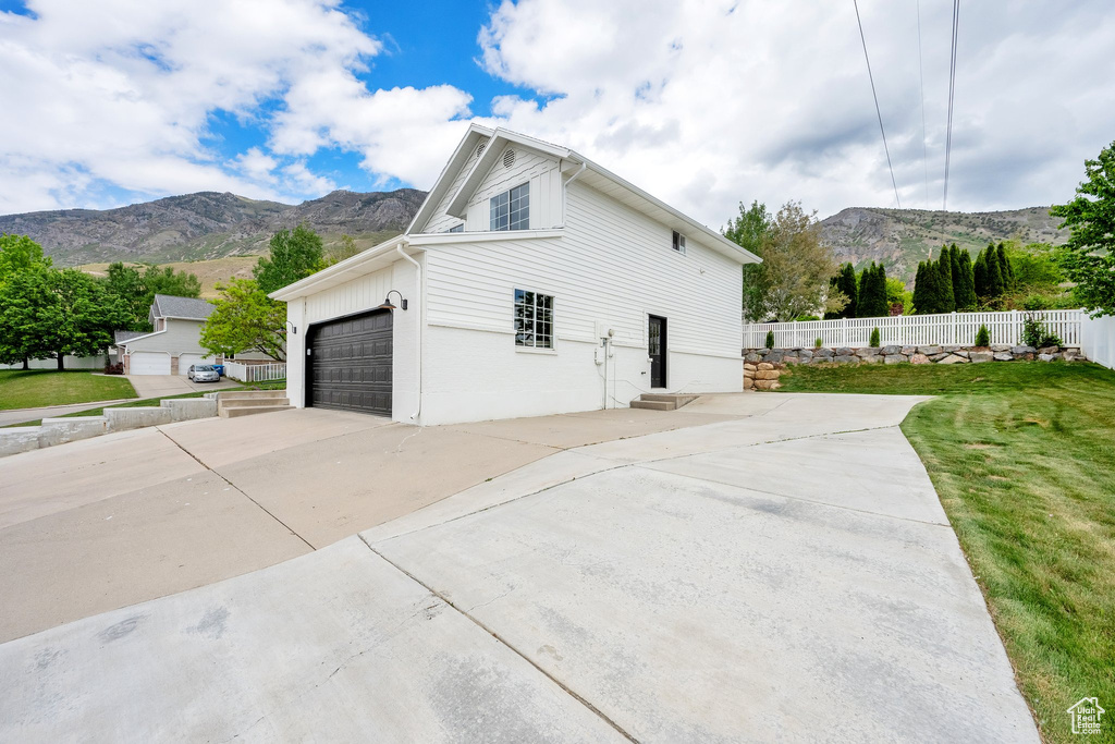 View of side of home featuring a mountain view, driveway, and an attached garage