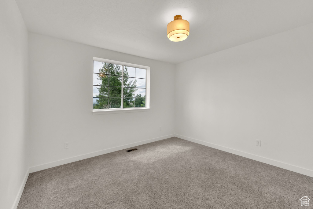 Spare room featuring carpet flooring and baseboards