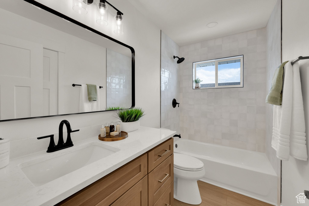 Bathroom featuring toilet, shower / washtub combination, vanity, and wood finished floors