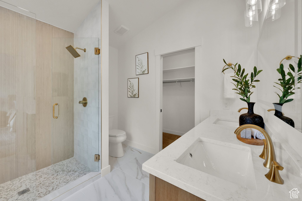 Bathroom featuring a stall shower, vaulted ceiling, toilet, marble finish flooring, and double vanity