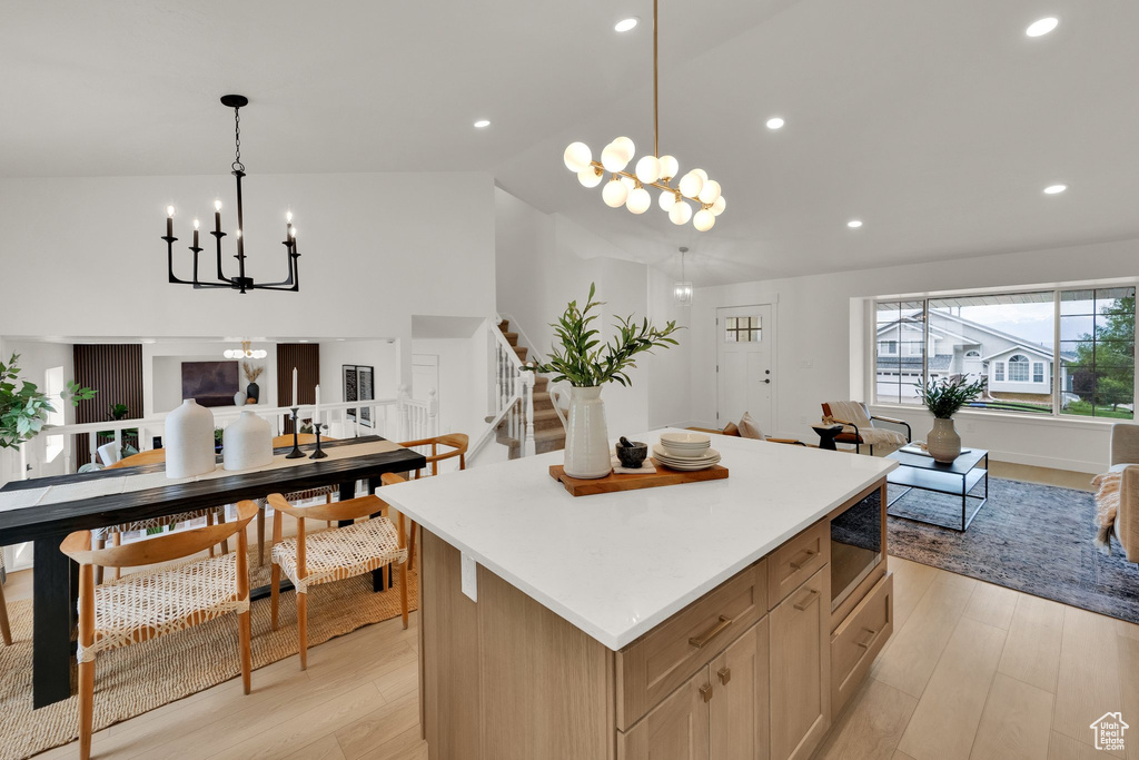 Kitchen featuring a chandelier, open floor plan, built in microwave, a center island, and lofted ceiling