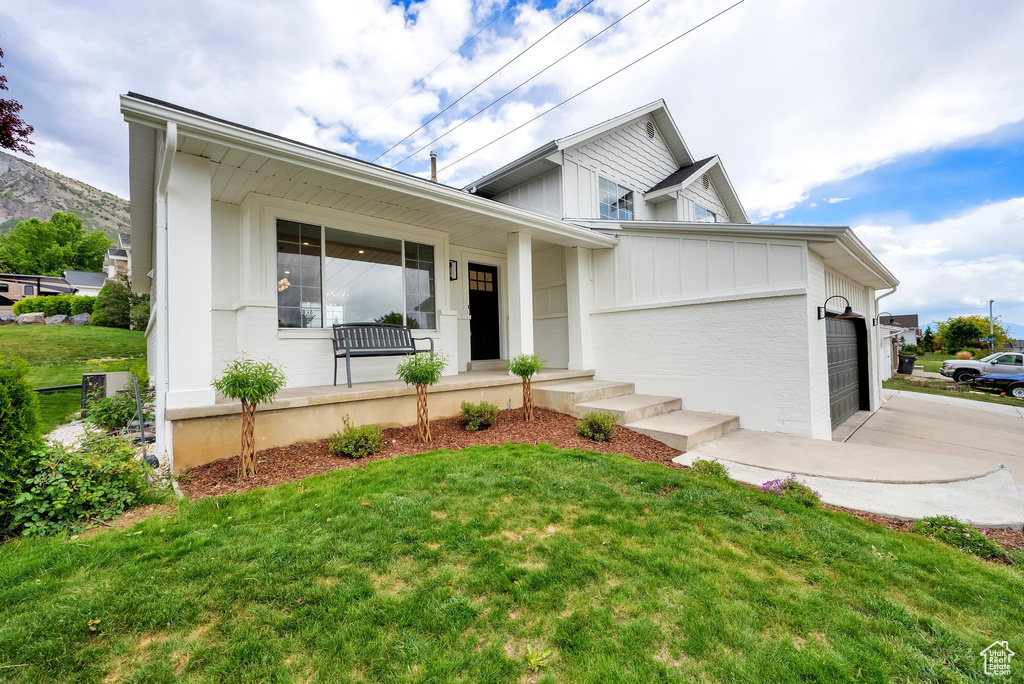 View of front of home featuring a garage, a porch, board and batten siding, and a front yard