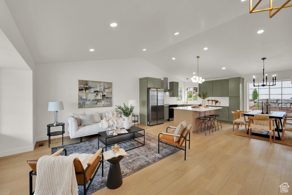 Living room with a chandelier, vaulted ceiling, light wood-style floors, recessed lighting, and baseboards