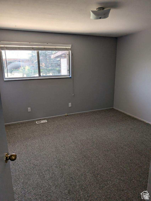 Carpeted spare room featuring baseboards