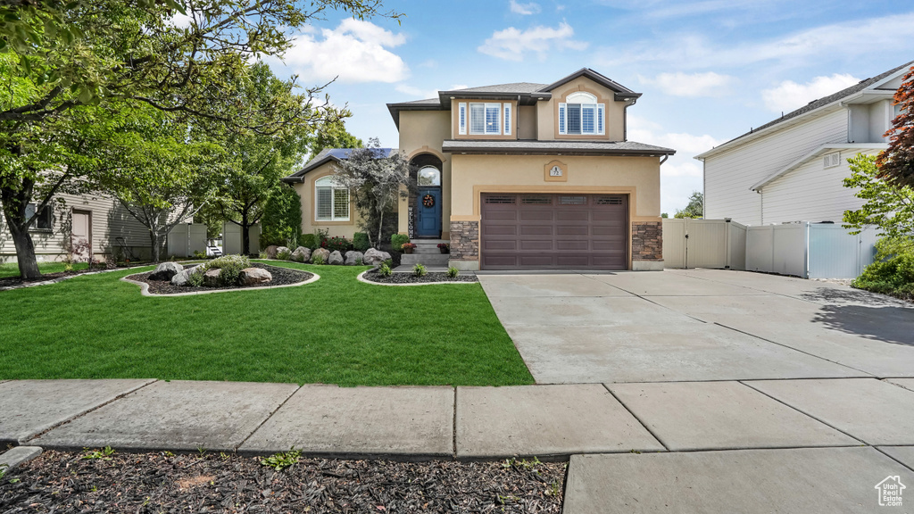 Traditional home featuring stucco siding, driveway, a garage, and stone siding