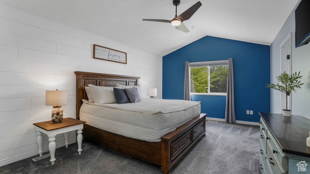 Bedroom featuring vaulted ceiling, dark colored carpet, and a ceiling fan