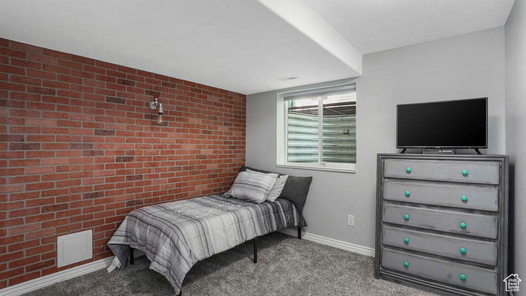 Carpeted bedroom featuring brick wall, baseboards, and an accent wall