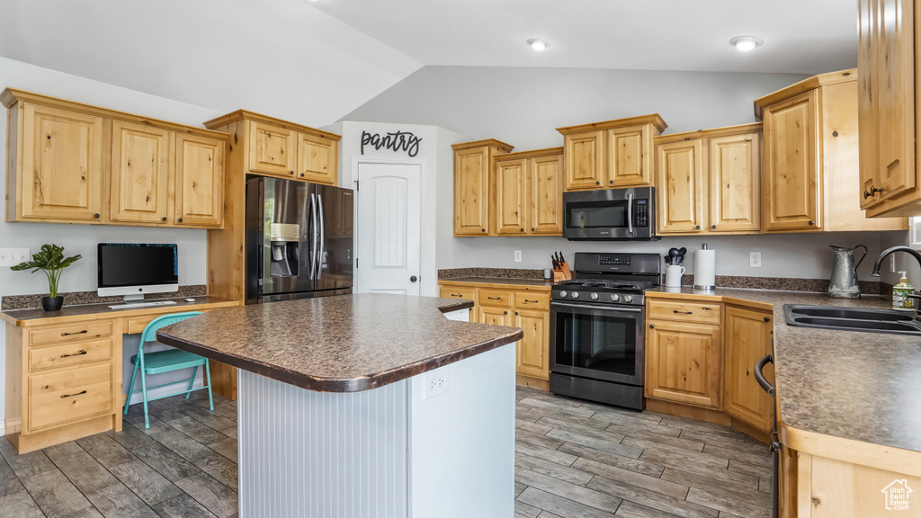 Kitchen featuring stainless steel appliances, a sink, lofted ceiling, dark countertops, and light wood-style flooring