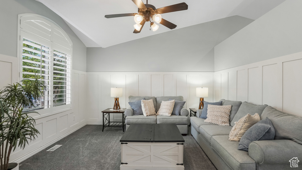 Living area featuring a decorative wall, ceiling fan, vaulted ceiling, wainscoting, and carpet