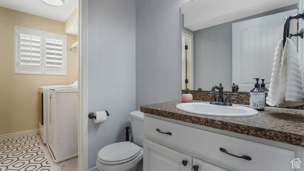 Bathroom featuring washer and clothes dryer, toilet, vanity, and baseboards