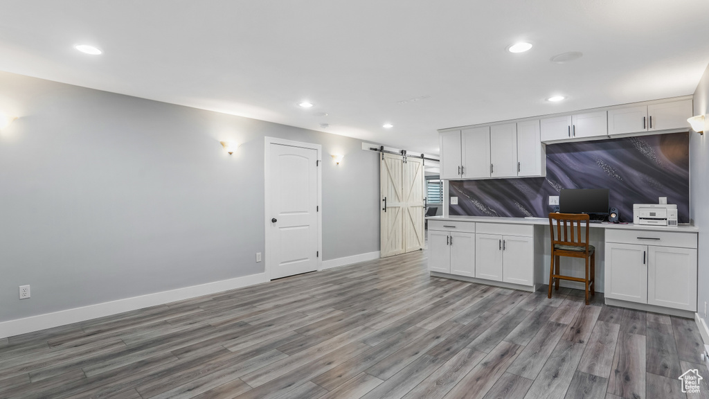Kitchen with a barn door, wood finished floors, recessed lighting, baseboards, and a desk