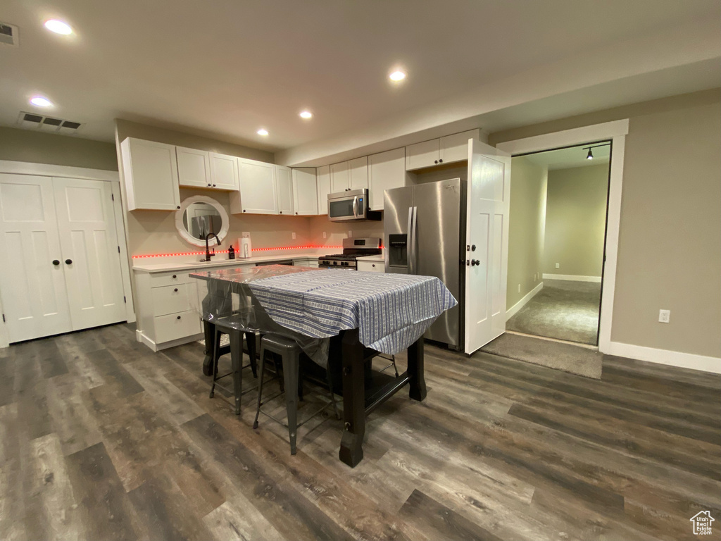 Kitchen featuring appliances with stainless steel finishes, baseboards, white cabinets, dark wood-style floors, and recessed lighting