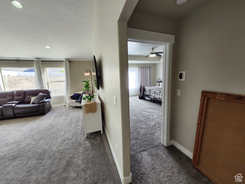 Hallway with dark colored carpet, arched walkways, recessed lighting, and baseboards