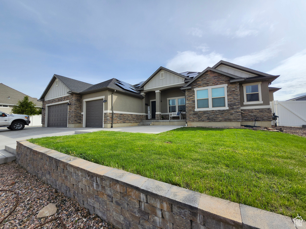 Craftsman house featuring board and batten siding, a garage, stone siding, roof mounted solar panels, and stucco siding