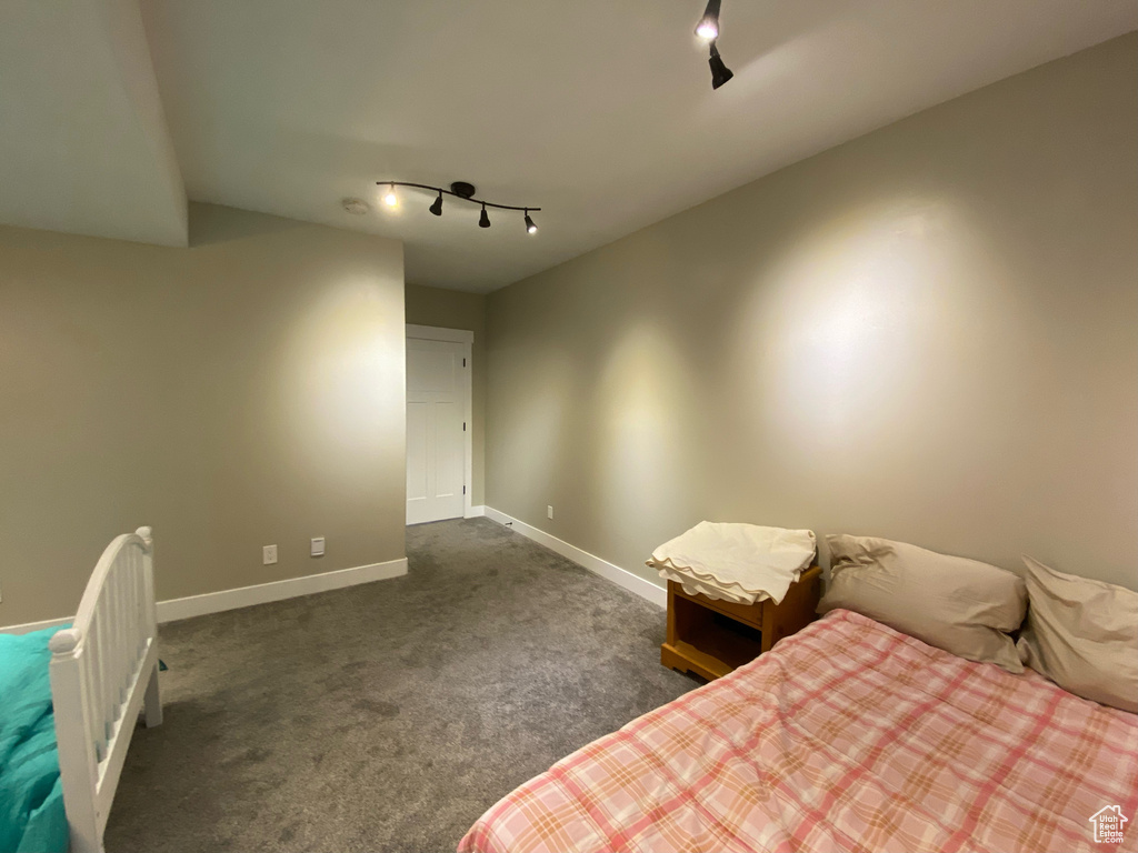 Bedroom featuring track lighting, dark colored carpet, and baseboards