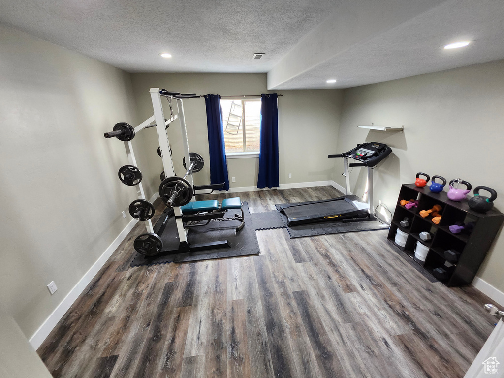 Exercise room with wood finished floors, a textured ceiling, recessed lighting, and baseboards