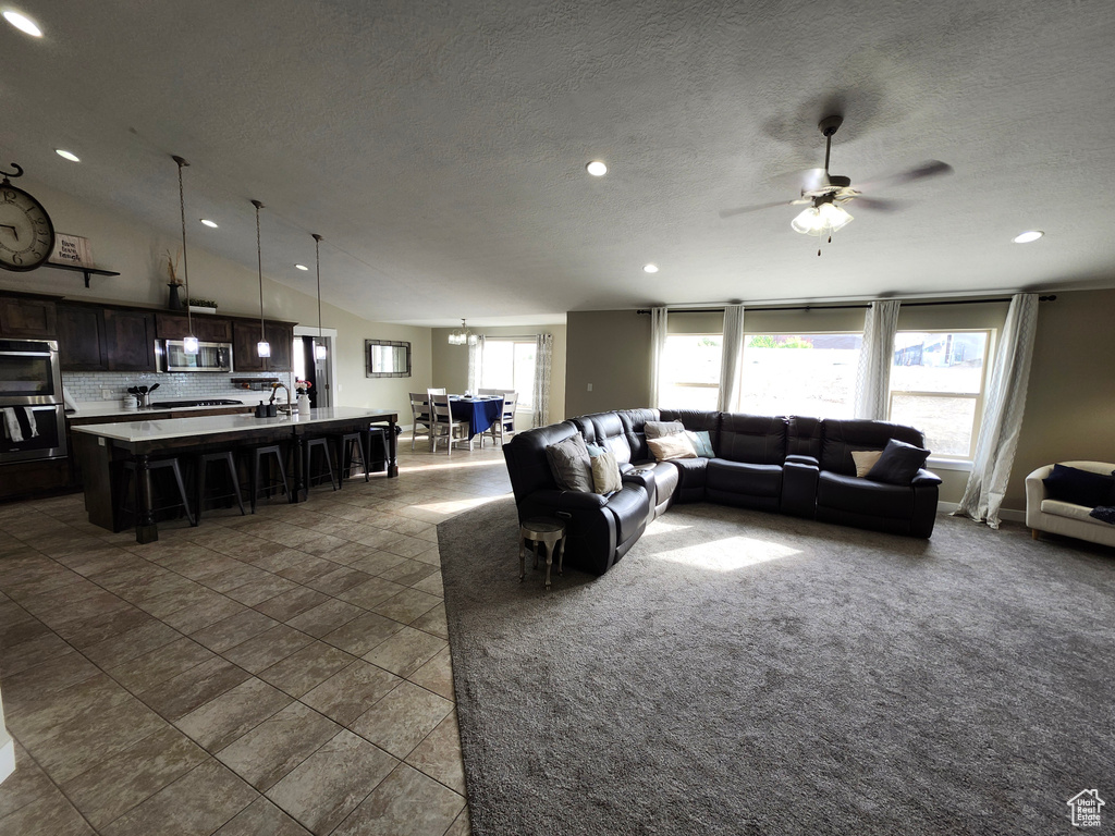 Living room featuring recessed lighting, ceiling fan, dark tile patterned flooring, vaulted ceiling, and a textured ceiling