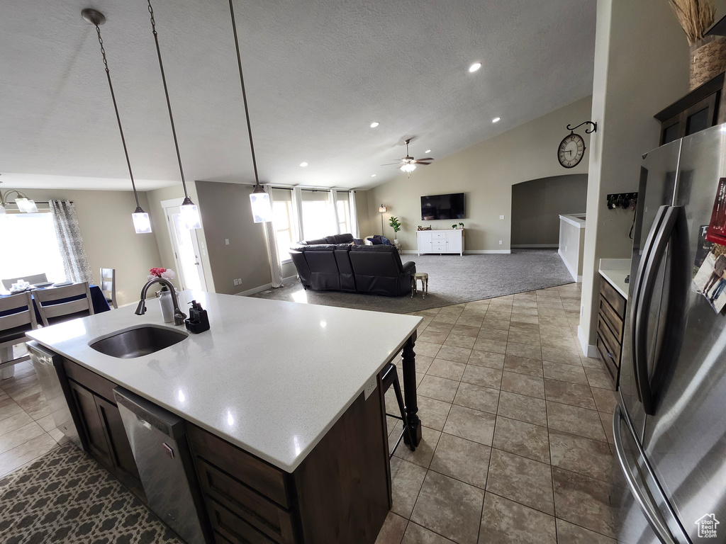 Kitchen with stainless steel appliances, a sink, ceiling fan, light countertops, and dark carpet