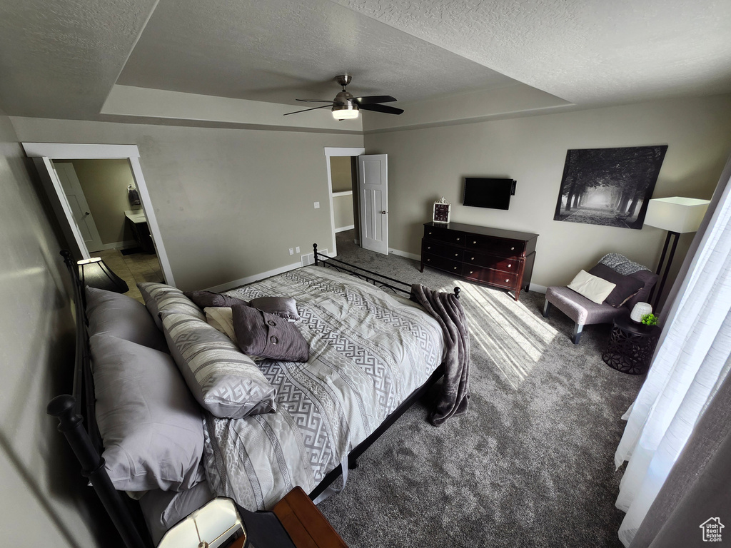 Carpeted bedroom featuring a textured ceiling, baseboards, and a ceiling fan